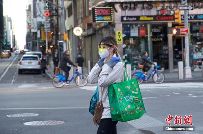 当地时间3月21日，美国纽约时代广场一位行人防护严密。中新社记者 廖攀 摄