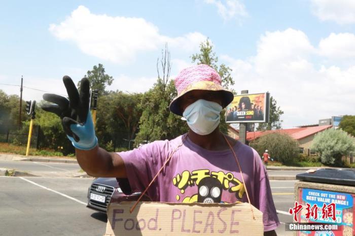 当地时间4日1日，南非约翰内斯堡，一名街头艺人佩戴防护口罩、手套。受疫情影响，南非已经实施全国范围“封城”。中新社记者 王曦 摄