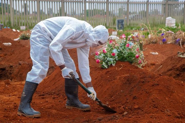 A man, dressed in protective clothing, works at a grave in Vlakfontein Cemetery on 8 January 2021.  